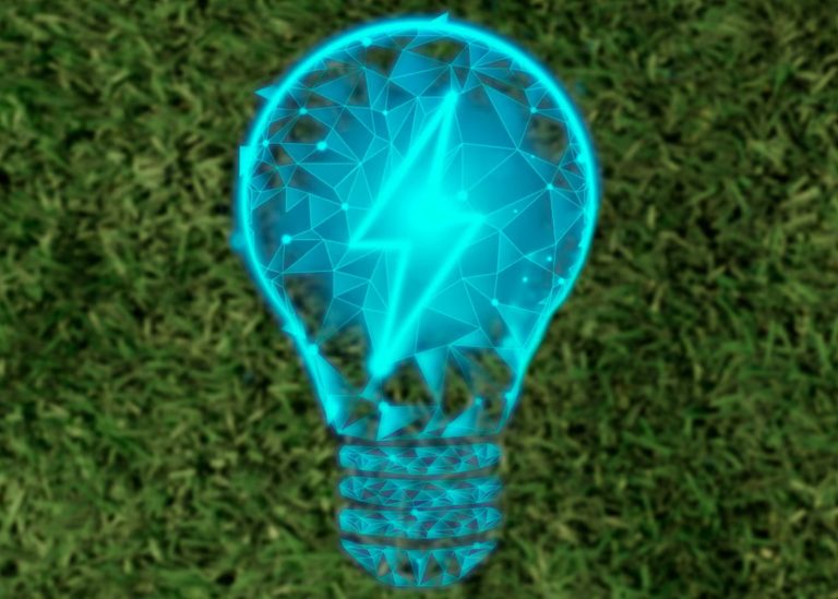 A glowing blue, wireframe-style lightbulb with a lightning bolt inside against a green grass background.