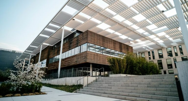 A modern commercial building with concrete steps and a large canpy rooftop structure